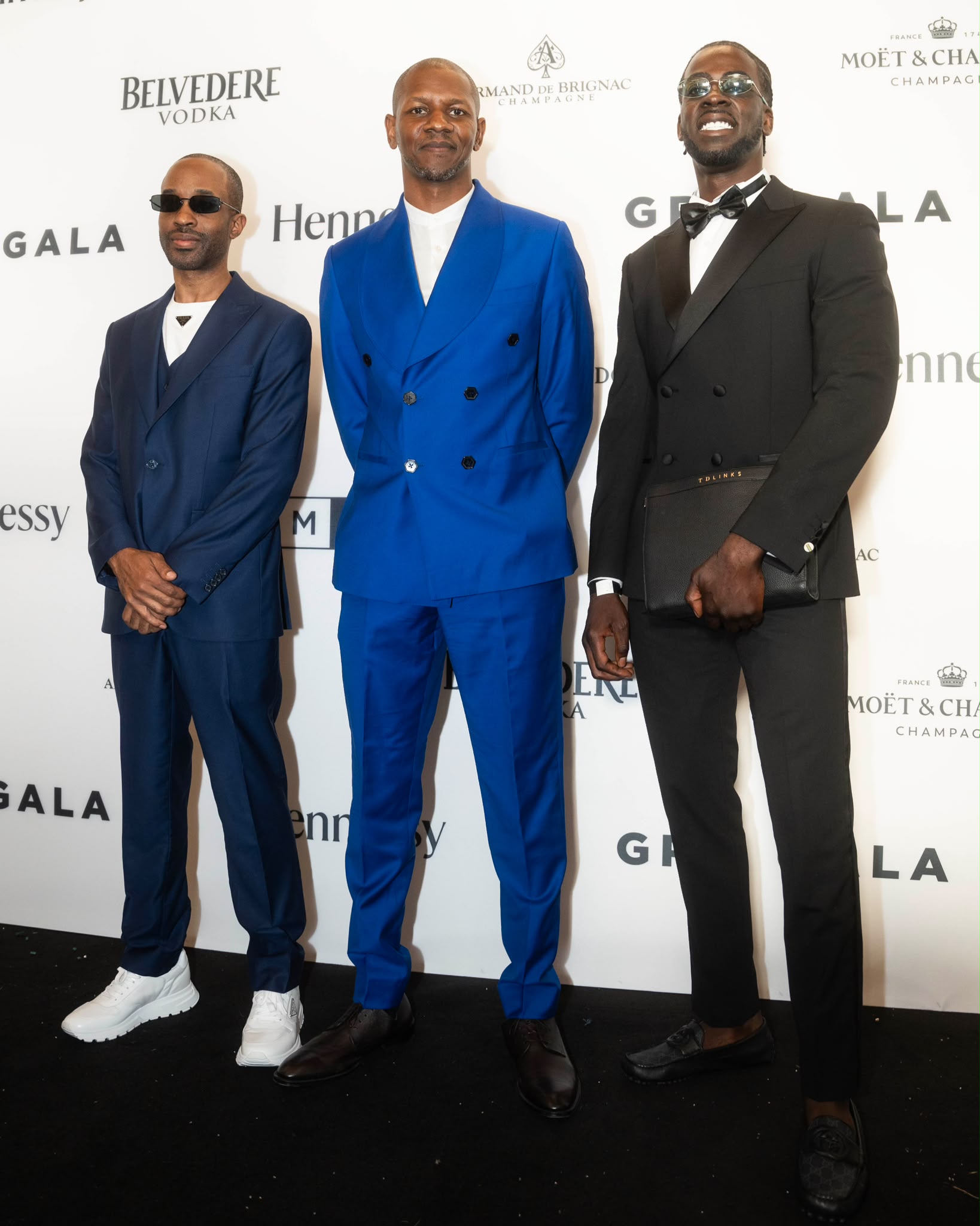 Raver on the red carpet at a black-tie gala with two collaborators